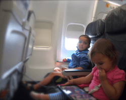 kids on a plane watching a movie